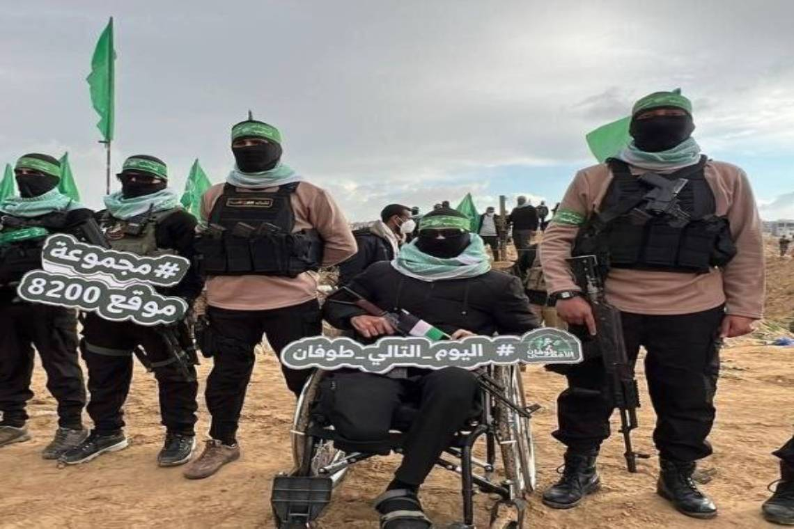 بترت ساقه خلال الحرب .. مقاتل قسامي يشارك في تسليم جثامين أسرى الاحتلال رافعاً عبارة &quot;اليوم التالي للطوفان&quot;.